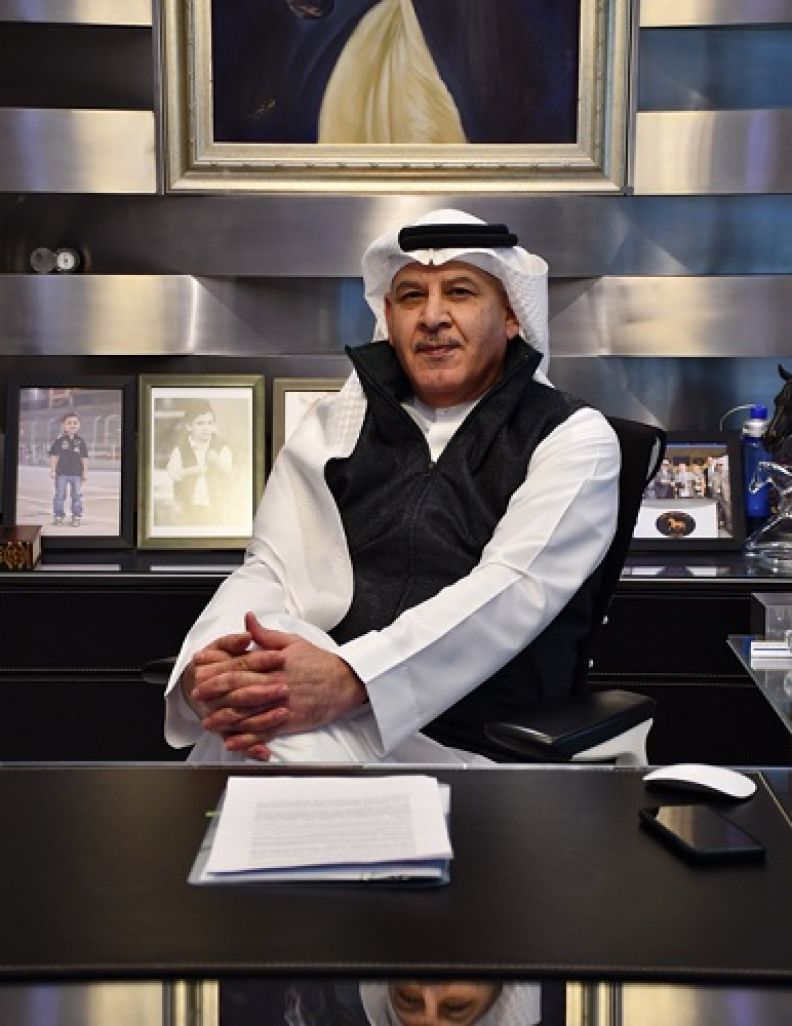 A profile picture of Khalid Abdul Rahim, a GCU alumnus, and founder and chairman of KAR Group, at his office desk, sitting in full traditional Bahraini dress.