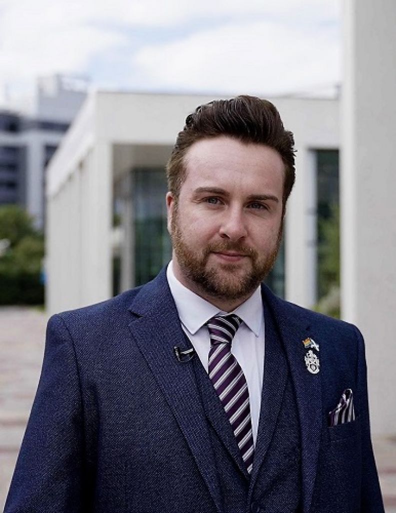 A portrait image of Ross McGhee, a GCU alumnus and President of the Society of Radiographers 2022/23, in front of building in the GCU Glasgow campus.