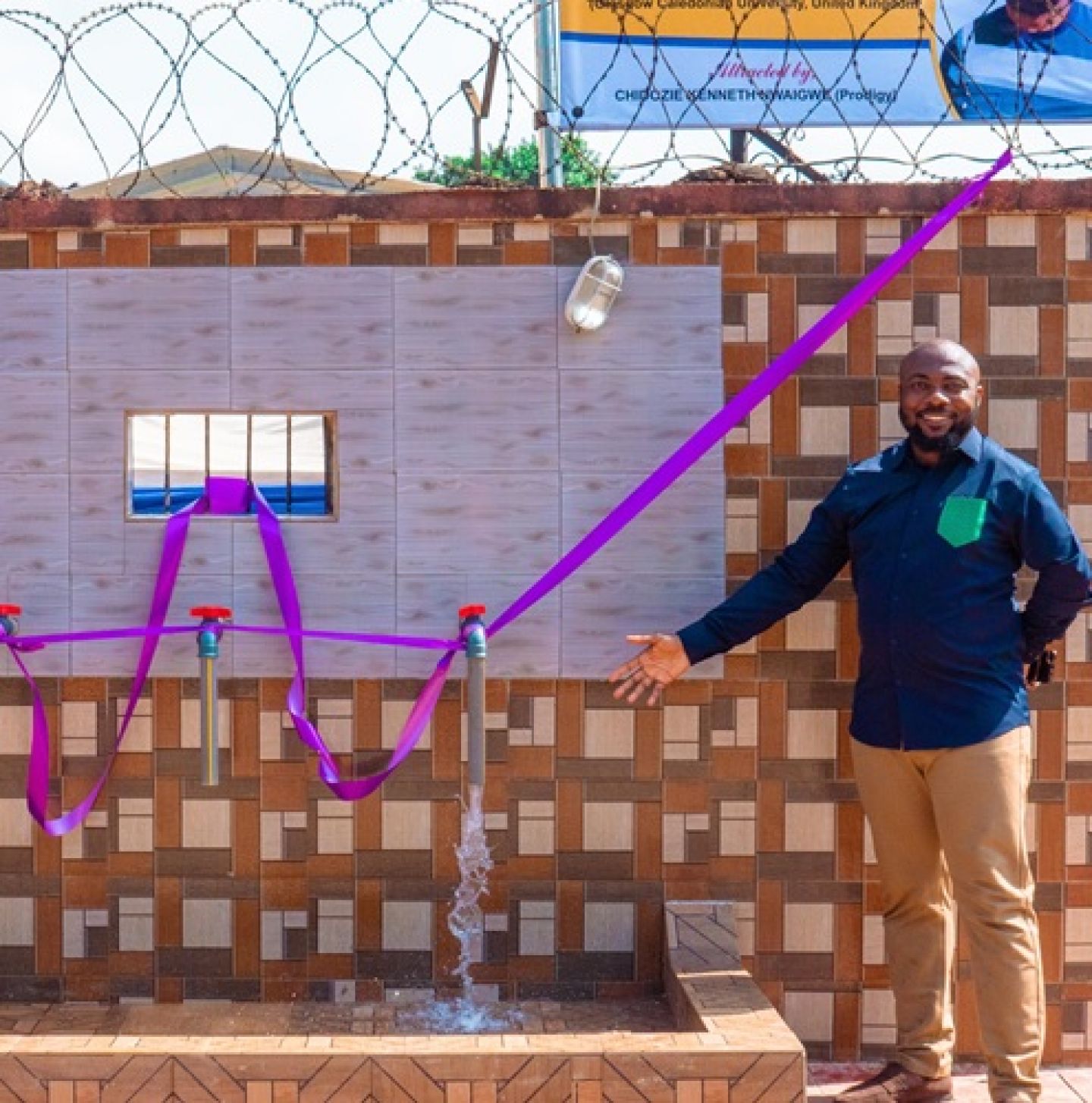 An image of GCU Graduate Chidozie Nwaigwe standing by a clean water pipe he provided for his home community in Nigeria.