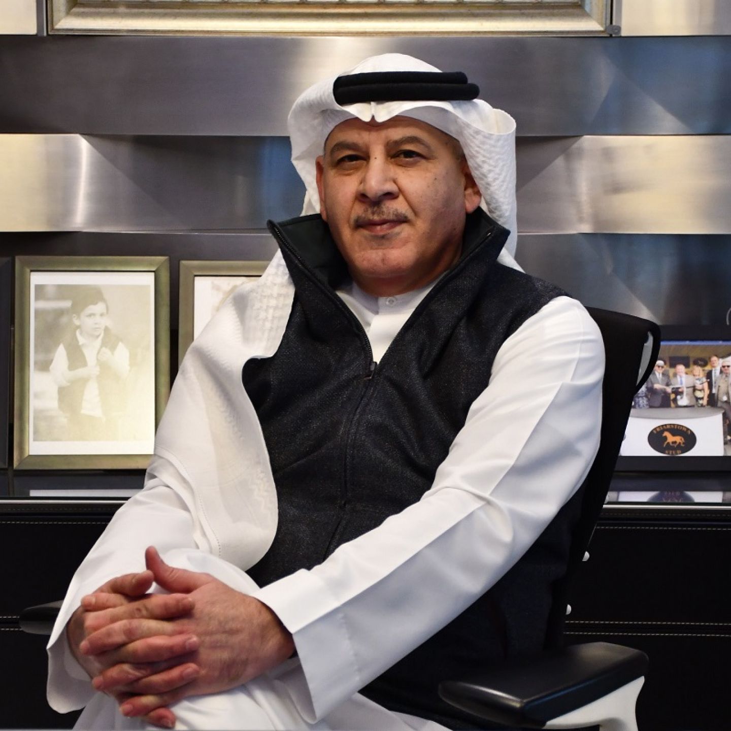 A profile picture of Khalid Abdul Rahim, a GCU alumnus, and founder and chairman of KAR Group, at his office desk, sitting in full traditional Bahraini dress.