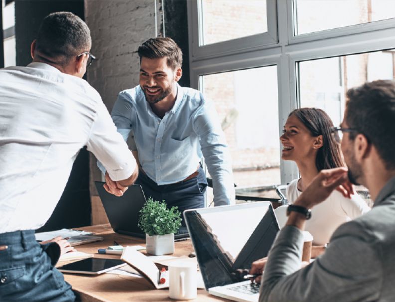 Businessmen in an office shaking hand across the table