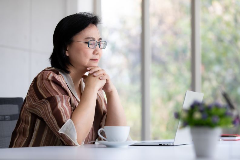 Woman with her eyes closed in a pensive posture while sitting at table with cup of tea