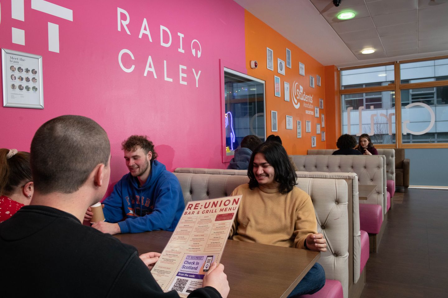 GCU students sitting at a table in the Re:Union Bar and Grill on Glasgow campus. Photo taken in December 2021.