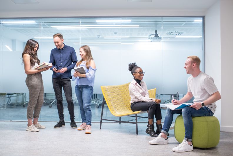 Group of Postgraduate students studying on laptops and chatting 