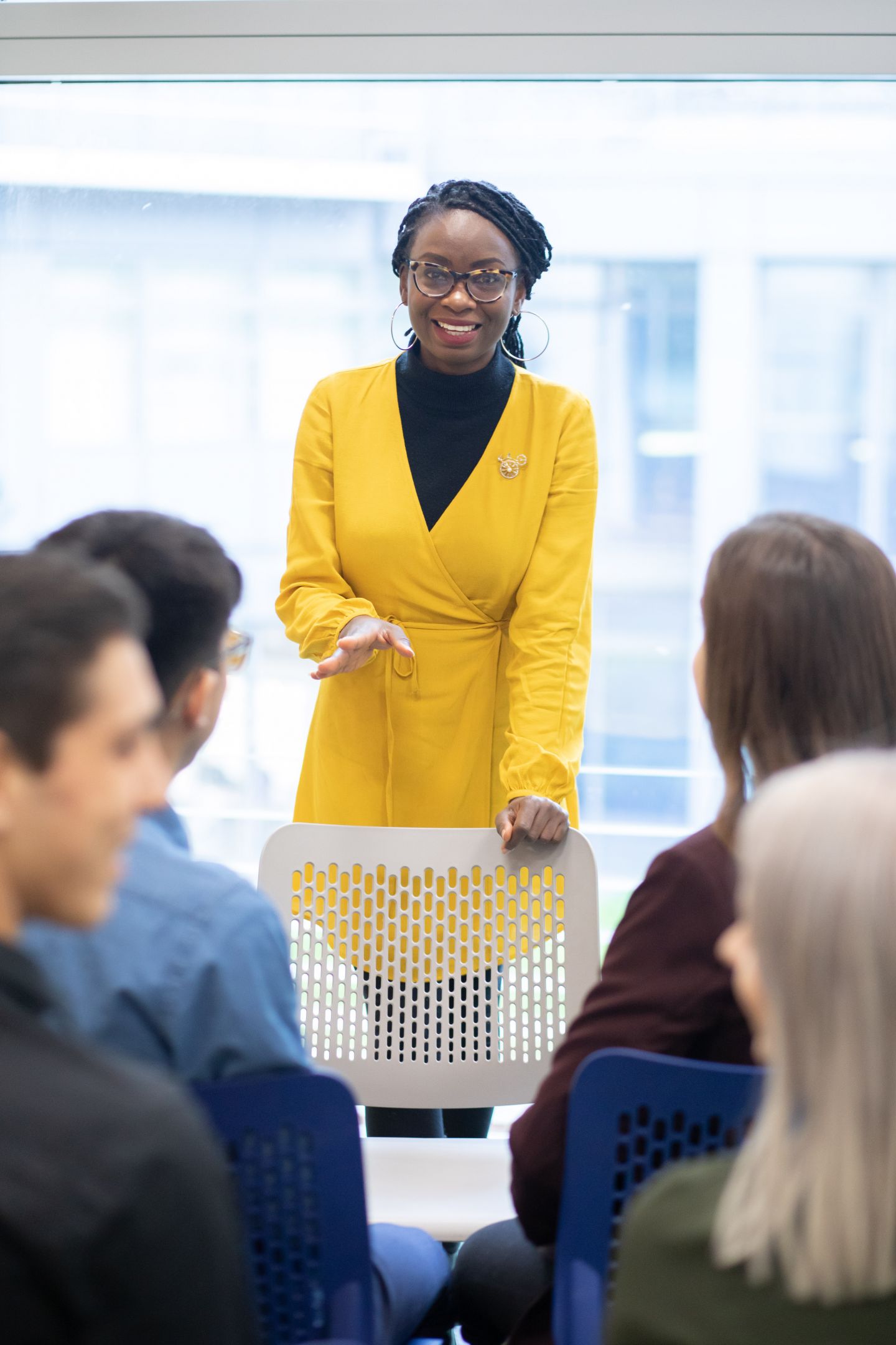 Portrait image of a student standing up and speaking to a group of students sitting down