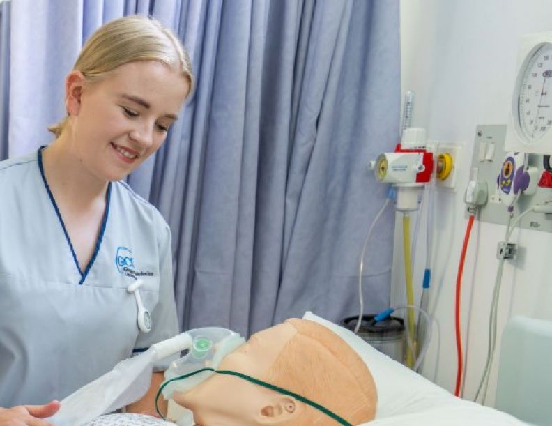 A photo of a student nurse attending to a medical manikin.