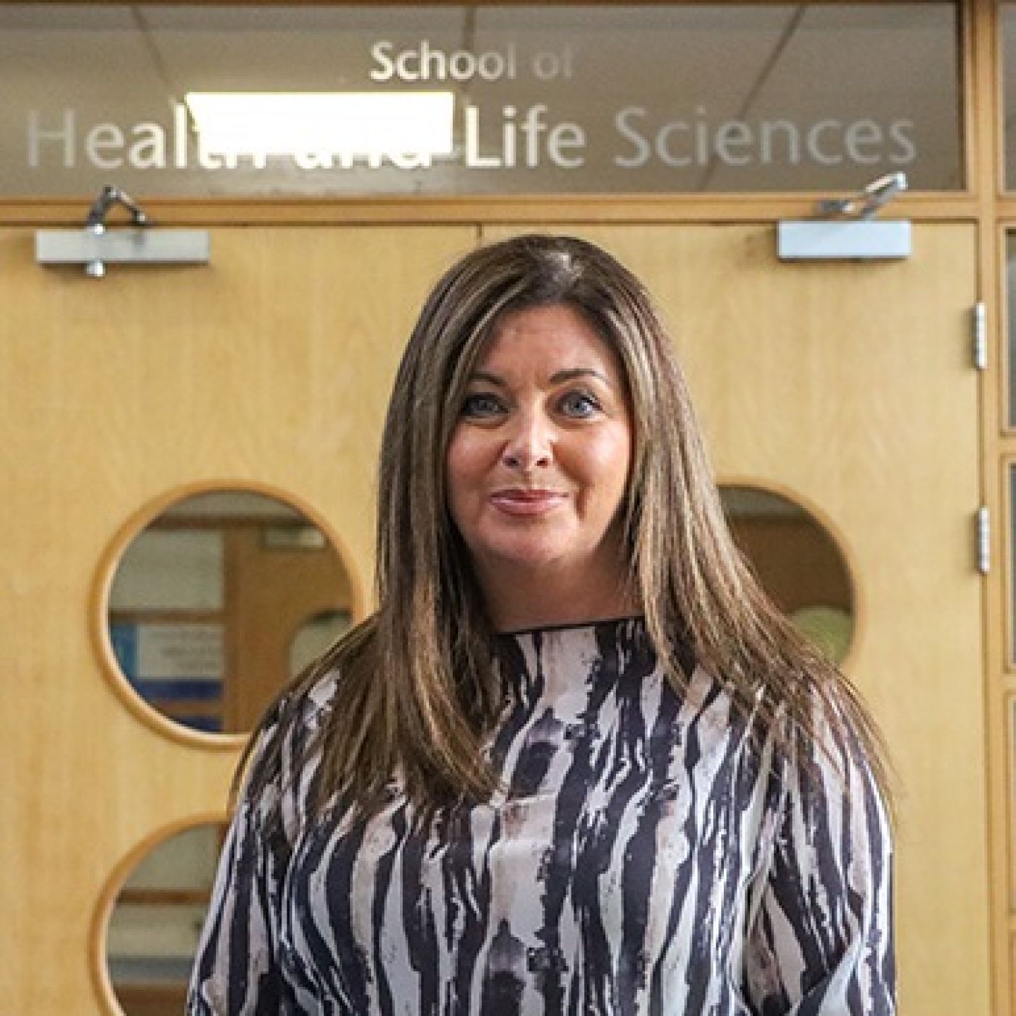 A square photo of Deborah Clark, GCU alumna and Radiography graduate, in front of the School of Health and Life Sciences on Glasgow campus.