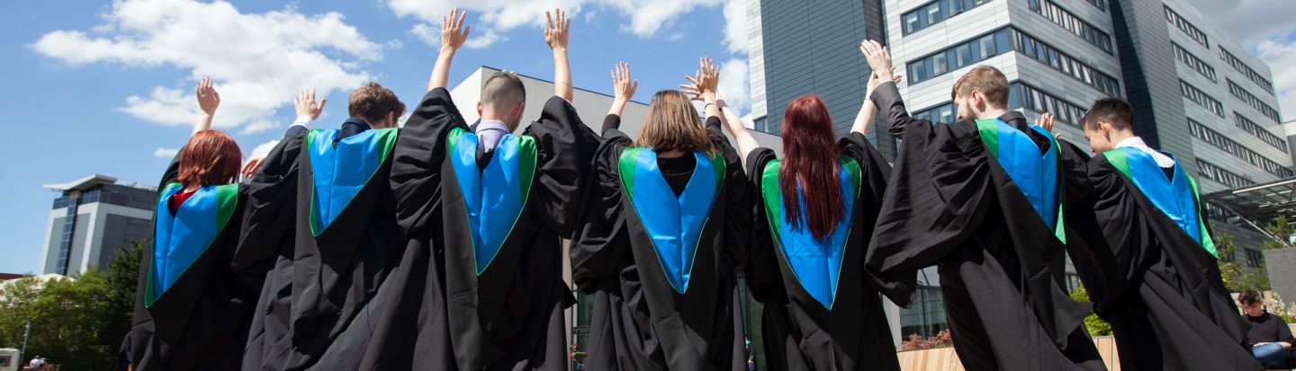 Group of students in their Graduation robes in front of campus