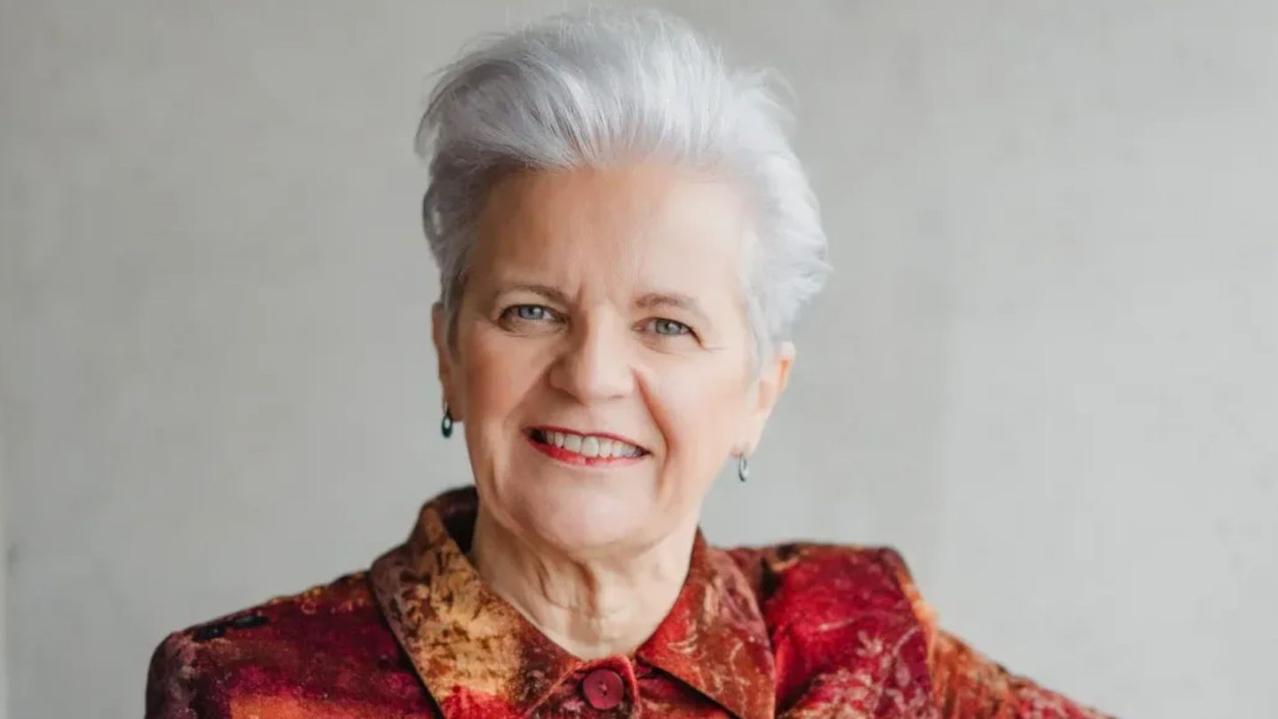 A photo of Margaret Gibson OBE smiling against a grey background