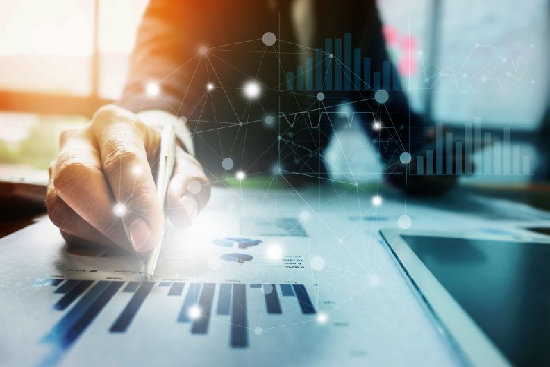 Close up Businessman hand holding pen and pointing at financial paperwork with financial network diagram