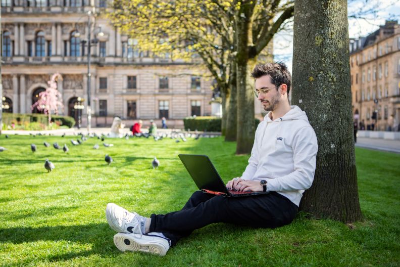 picture of student on the green in george square with laptop